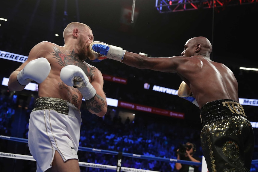 Floyd Mayweather punches Conor McGregor in the face.