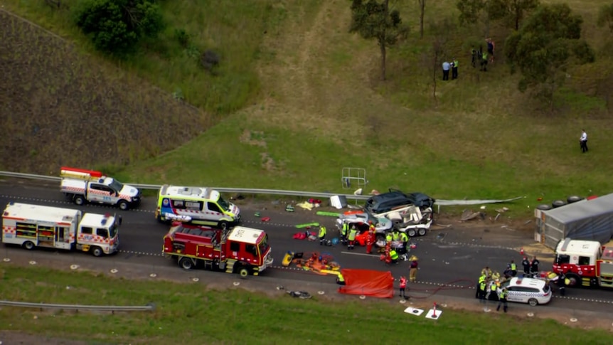 Emergency services surround overturned truck and crashed vehicles.