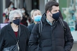 Various people walk through Canberra wearing facemasks 