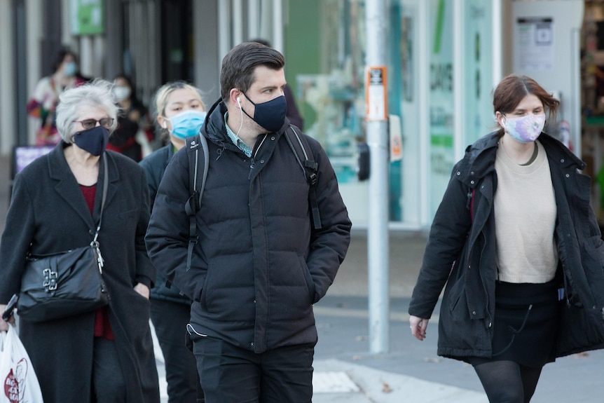 Different people walk through Canberra wearing face masks 