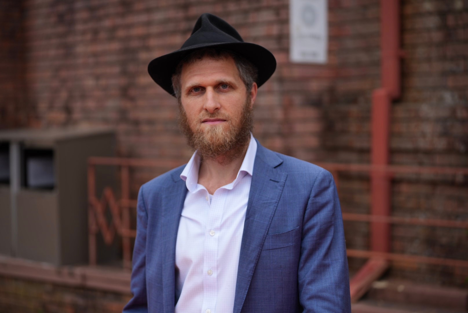 Hombre con sombrero negro y chaqueta de traje azul