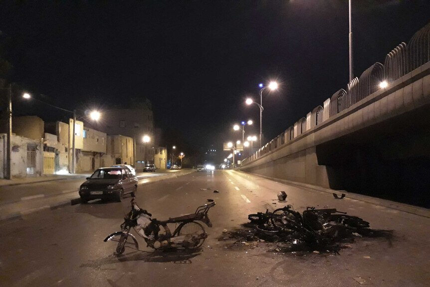 Scorched motorcycles remain on the street after a protest in Iran.