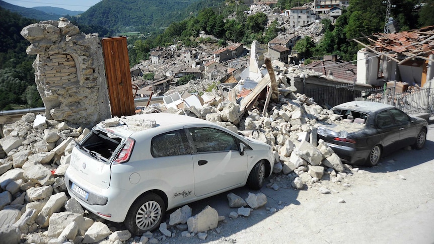 Cars sit amidst the rubble from earthquake damaged buildings in the central Italian village of Pescara del Tronto