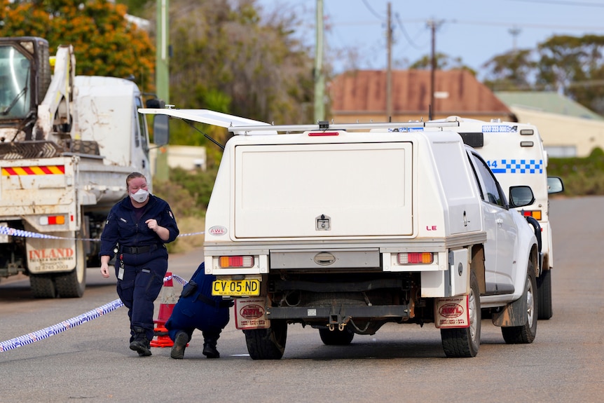 A woman in blue forensic gear and a mask at a crime scene in Broken Hill. 