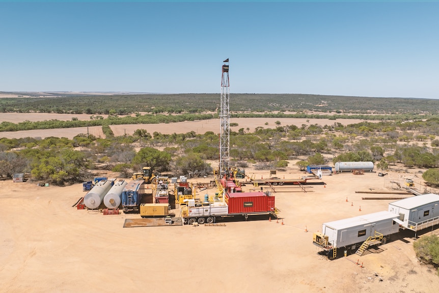 A drone shot of machinery in a paddock near a gas well 