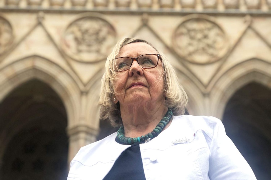 Beth Heinrich stands outside a church in Brisbane, looks up towards the sky