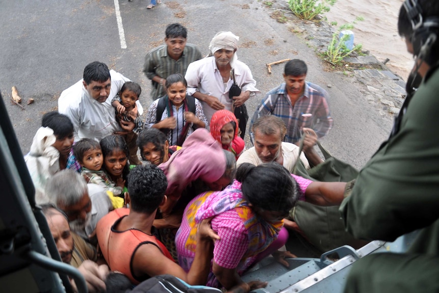 Indian villagers board an Indian Air Force helicopter as floodwaters rise