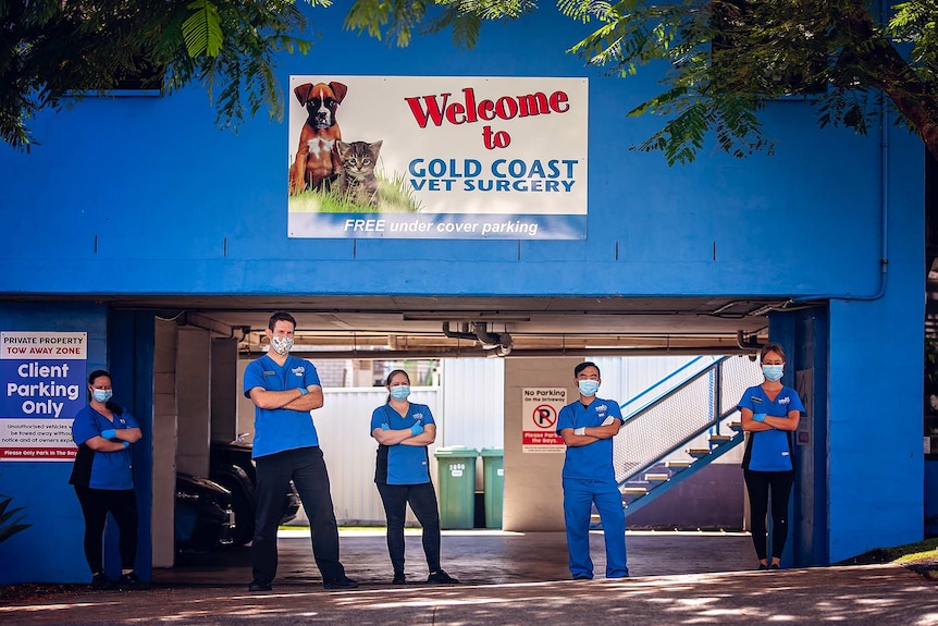 vet staff in blue shirts and masks are photographed in the driveway of their carpark