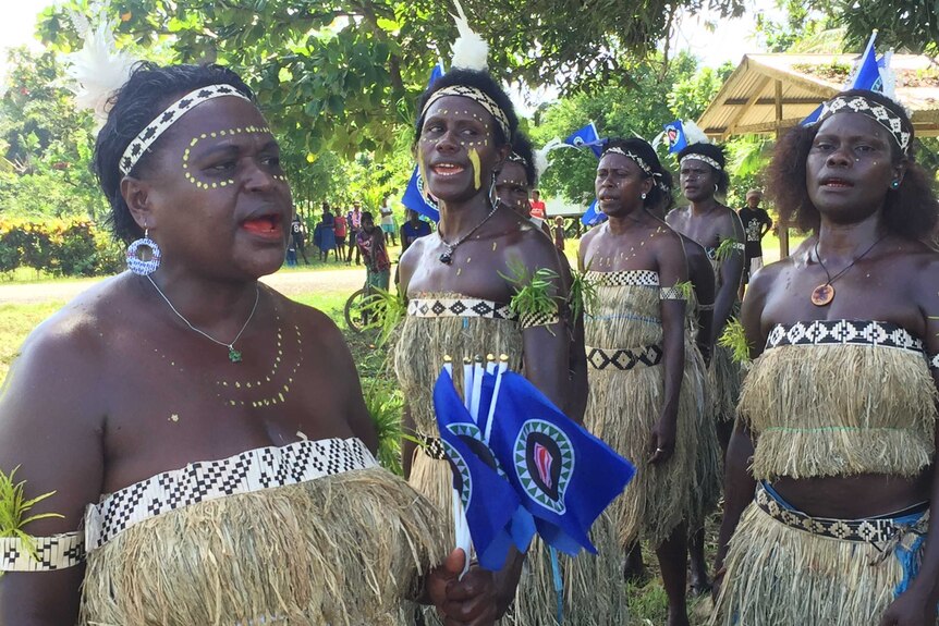 Women in tradition dress with flags and their bodies painted celebrate the opening of voting.