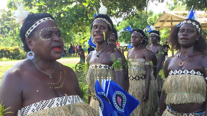 Women in tradition dress with flags and their bodies painted celebrate the opening of voting.