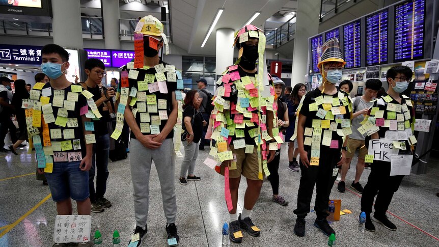 A group of young men in Hong Kong stand in a row covered in sticky notes