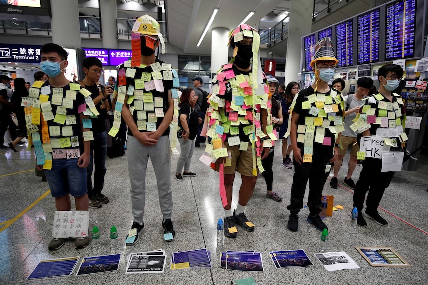 A group of young men in Hong Kong stand in a row covered in sticky notes