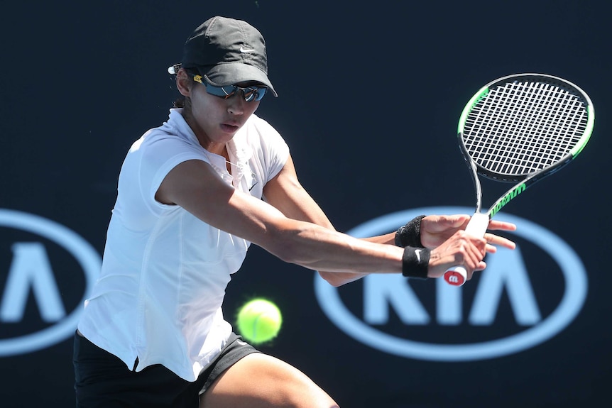 Tennis player plays a double-fisted backhand,