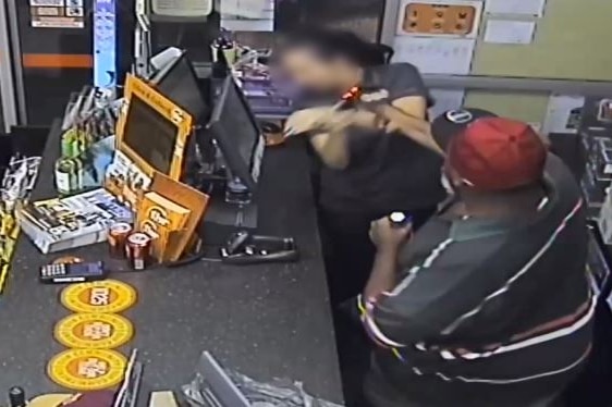 A man uses a bottle to smash a woman over the head during the armed robbery of a bottle shop