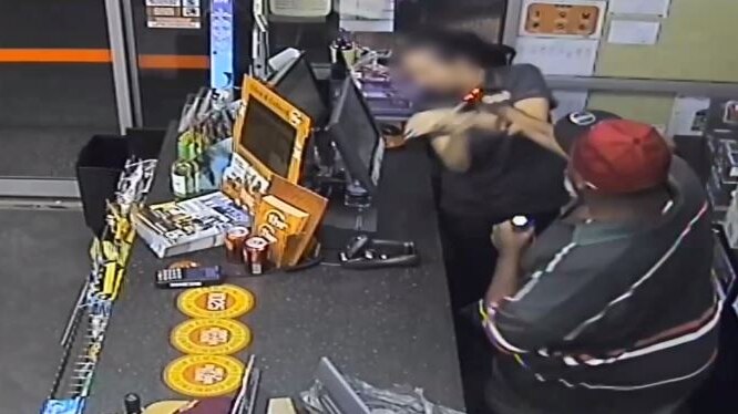 A man uses a bottle to smash a woman over the head during the armed robbery of a bottle shop