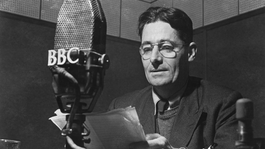 black and white, black-haired man reading from paper into a BBC microphone