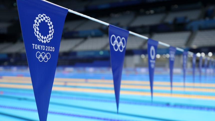 Blue flags on a string above a swimming pool with Tokyo 2020 on it.