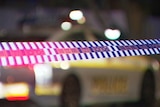Police crime scene tape with an out of focus police car behind