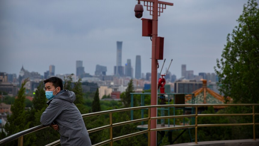 Man wears a face mask will standing on a hilltop in Beijing.