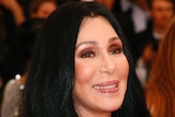 Cher arrives at an event with a big smile on her face.