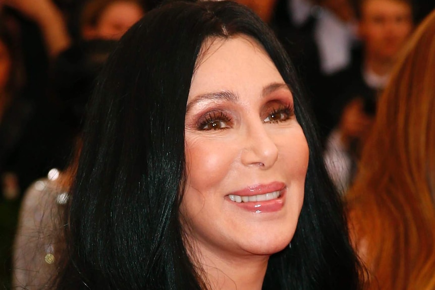Cher arrives at an event with a big smile on her face.
