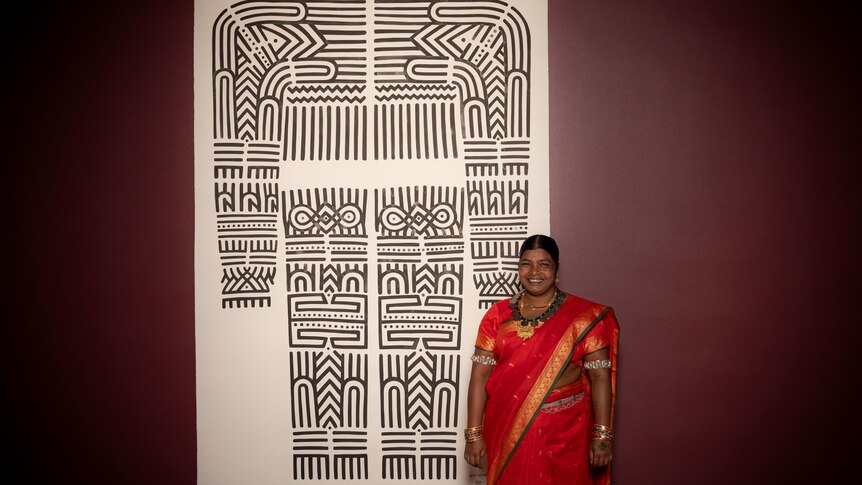 Indian woman standing with her artwork.