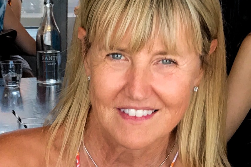 A close up photo of Sarah Jenkins, who has blonde hair and blue eyes and is wearing a red floral dress