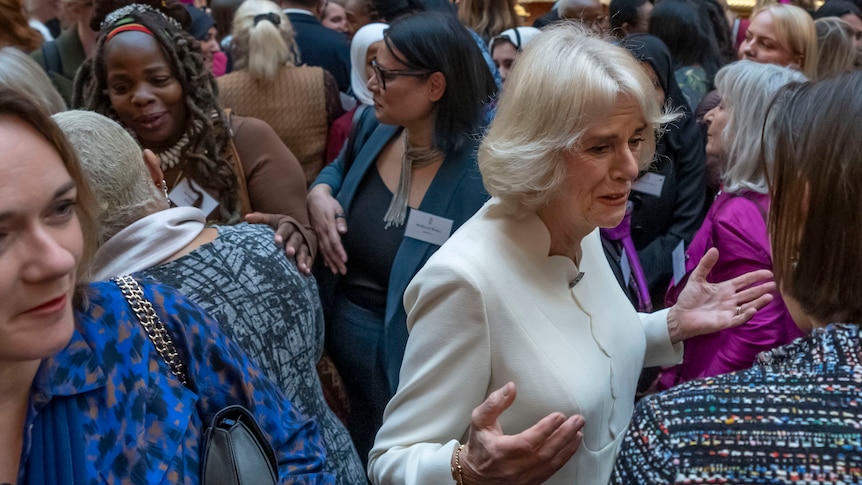 A large group of people in a crowd with Queen Consort Camila in the centre. 