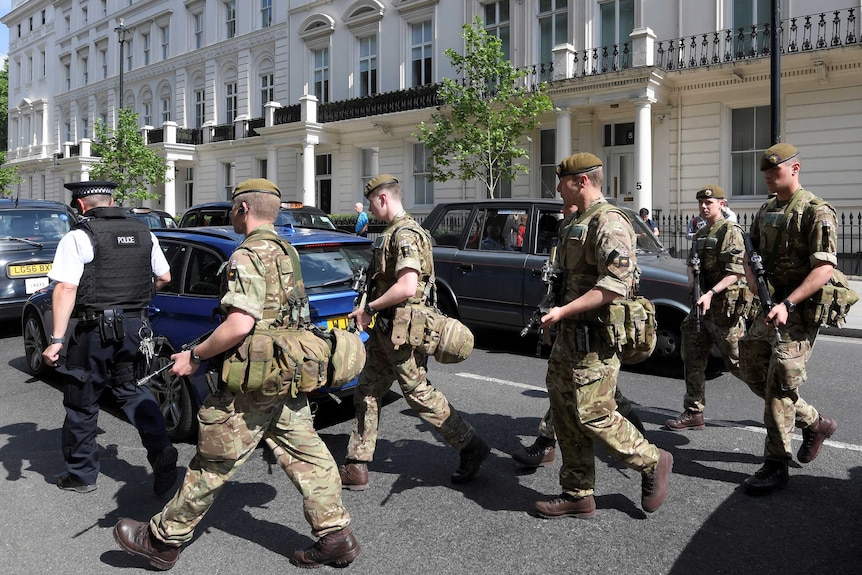 Soldiers cross a road with a police officer in central London.