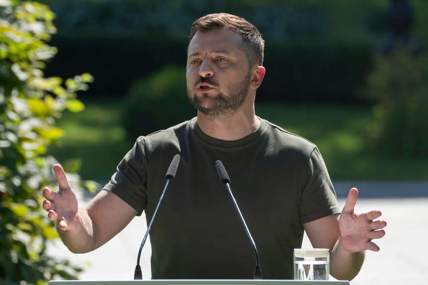 Volodymyr Zelenskyy speaks at a news conference in Kyiv wearing a khaki t-shirt.