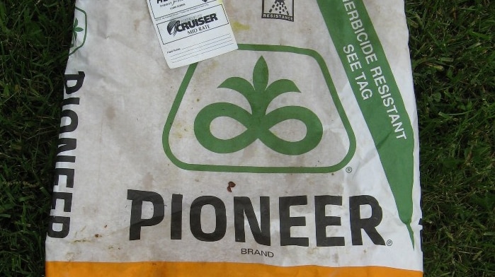 A close up shot of a bag of seed reading 'pioneer seed corn' and a tag with the patented gene technology the seeds contain