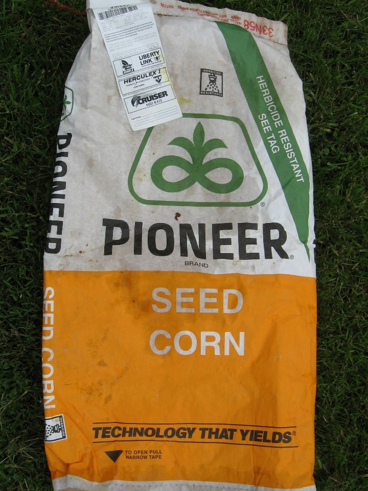 A close up shot of a bag of seed reading 'pioneer seed corn' and a tag with the patented gene technology the seeds contain