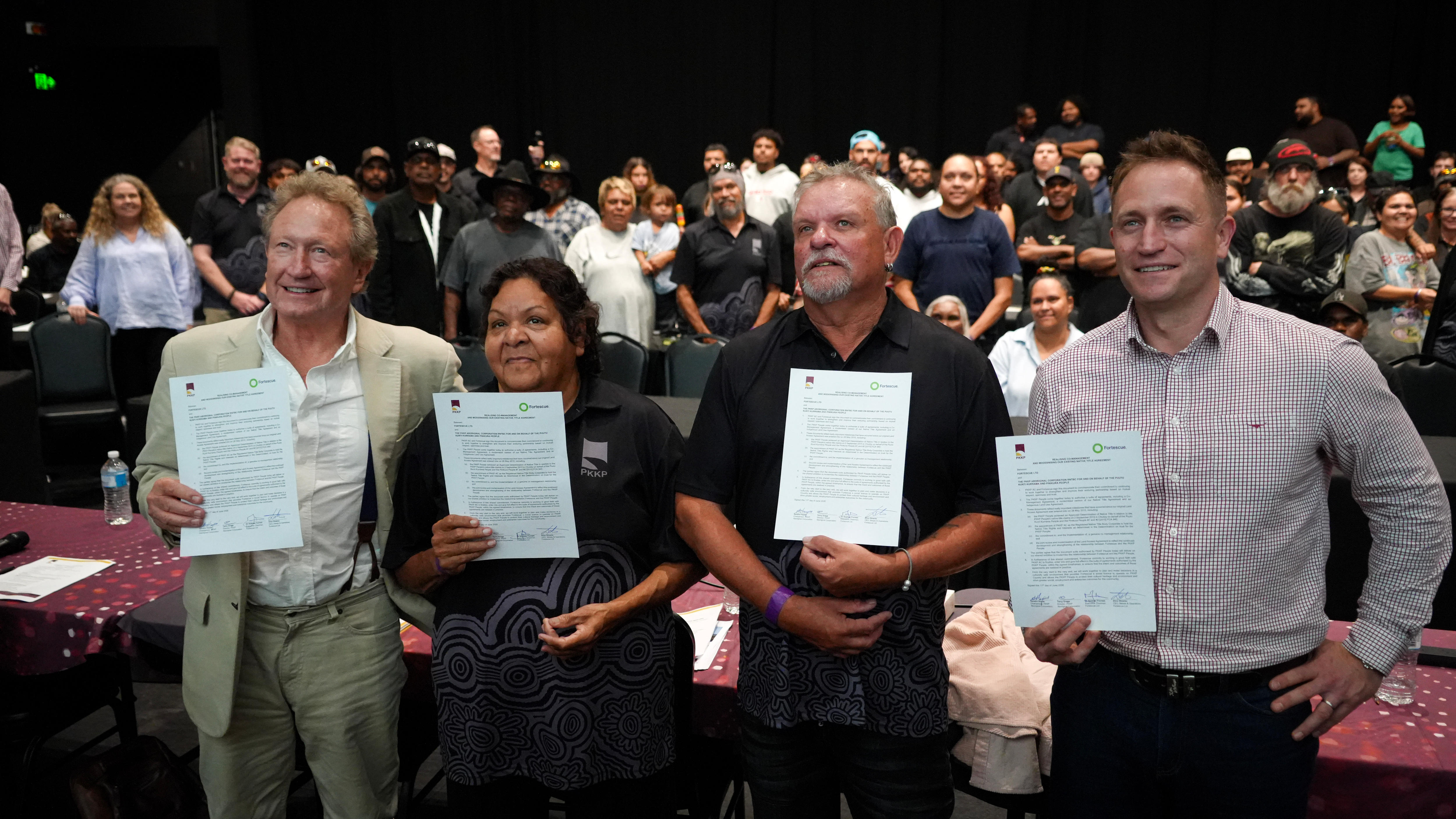 Andrew Forrest, PKKP elder Sandra Hayes, PKKP elder Terry Drage, and Fortescue CEO Dino Otranto hold up signed documents.
