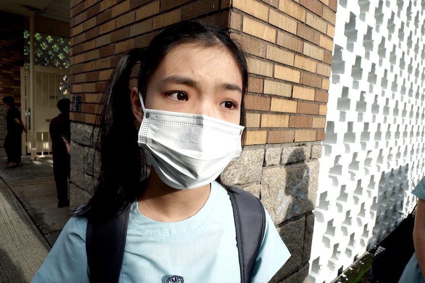 A girl in a wearing a t-shirt, backpack and face mask.