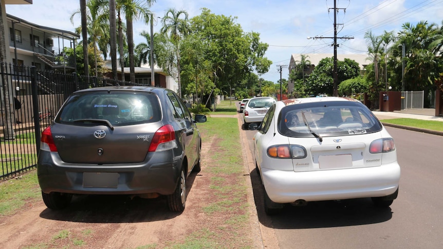 Cars parked on a residential verge outside a house.