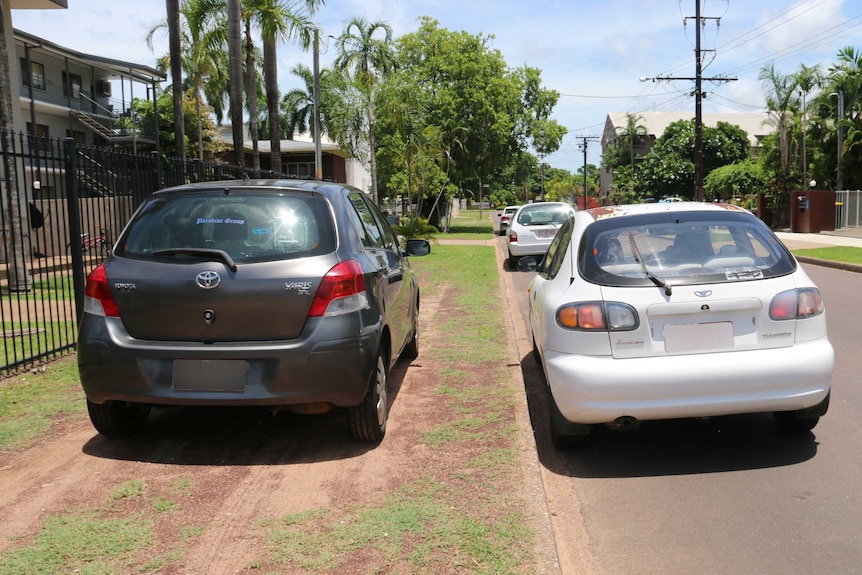 Cars parked on a residential verge outside a house.