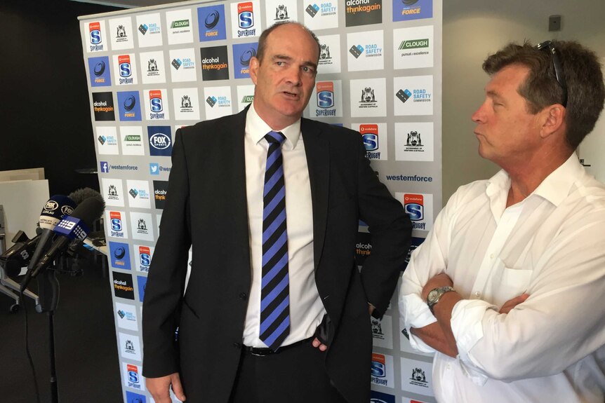 Western Force CEO Mark Sinderberry stands in front of a sponsors' board.