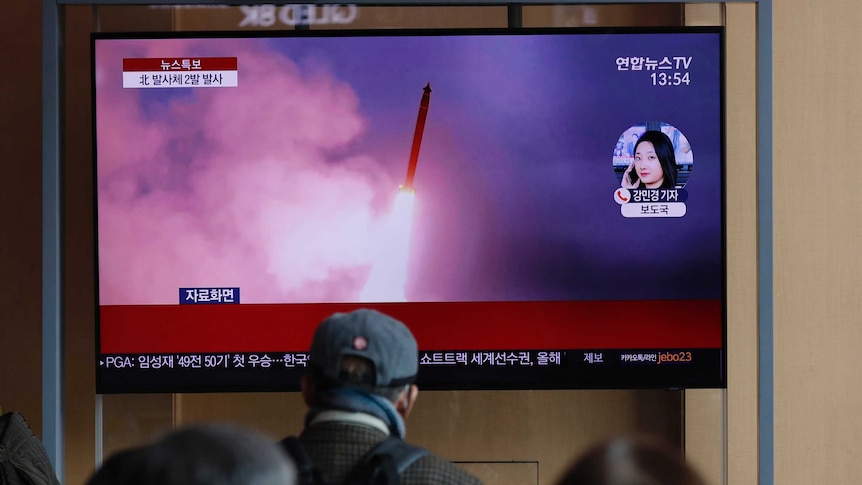 People watch a TV screen showing North Korea's firing of projectiles.