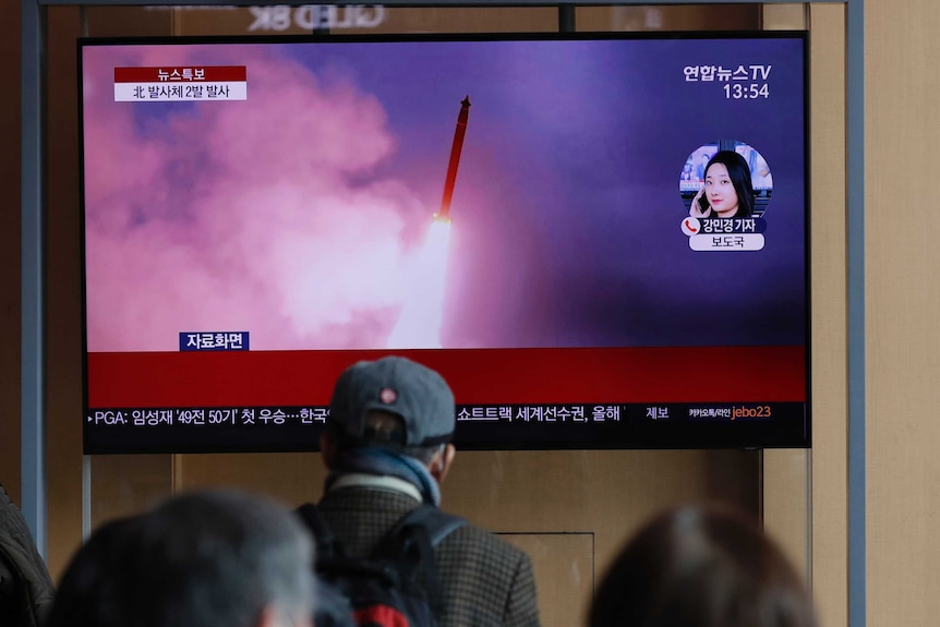 People watch a TV screen showing North Korea's firing of projectiles.