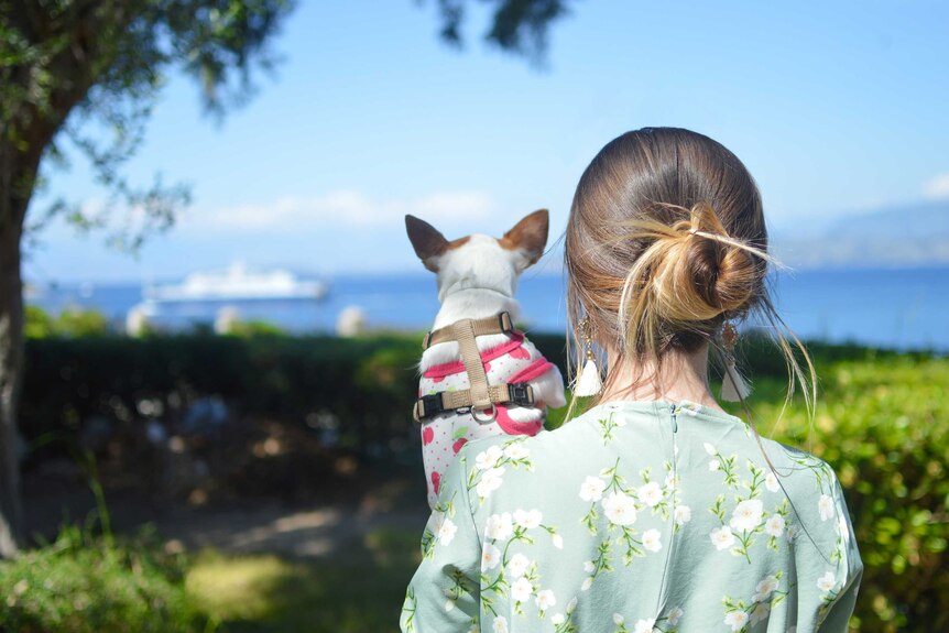 Woman holds her dog while admiring the view