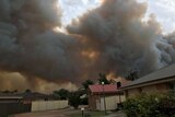 Smoke from a bushfire rises into the sky above houses in northern NSW.