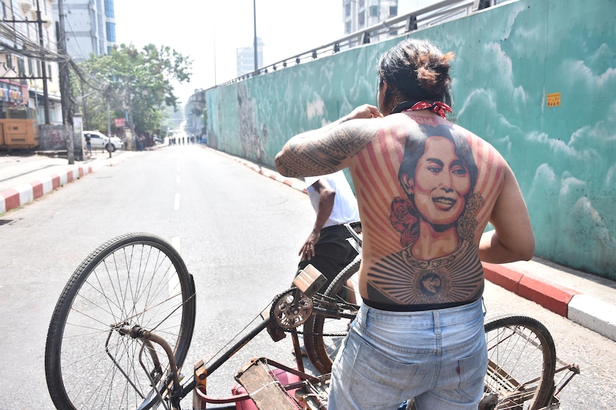 a man with the tattoo of a woman on his back looking down an alleyway