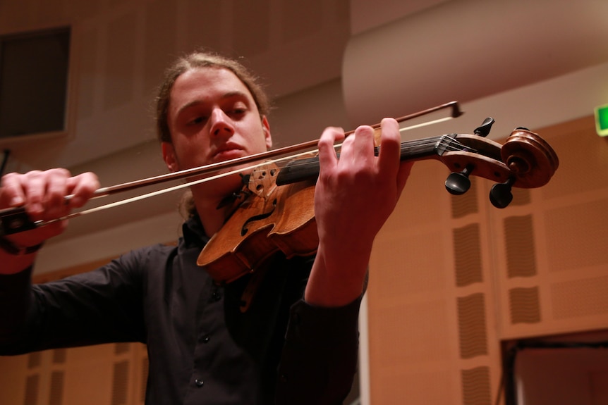 A young man plays a viola