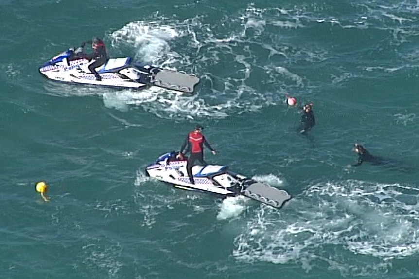 Police divers in the water off South Stradbroke Island with police on jetskis.