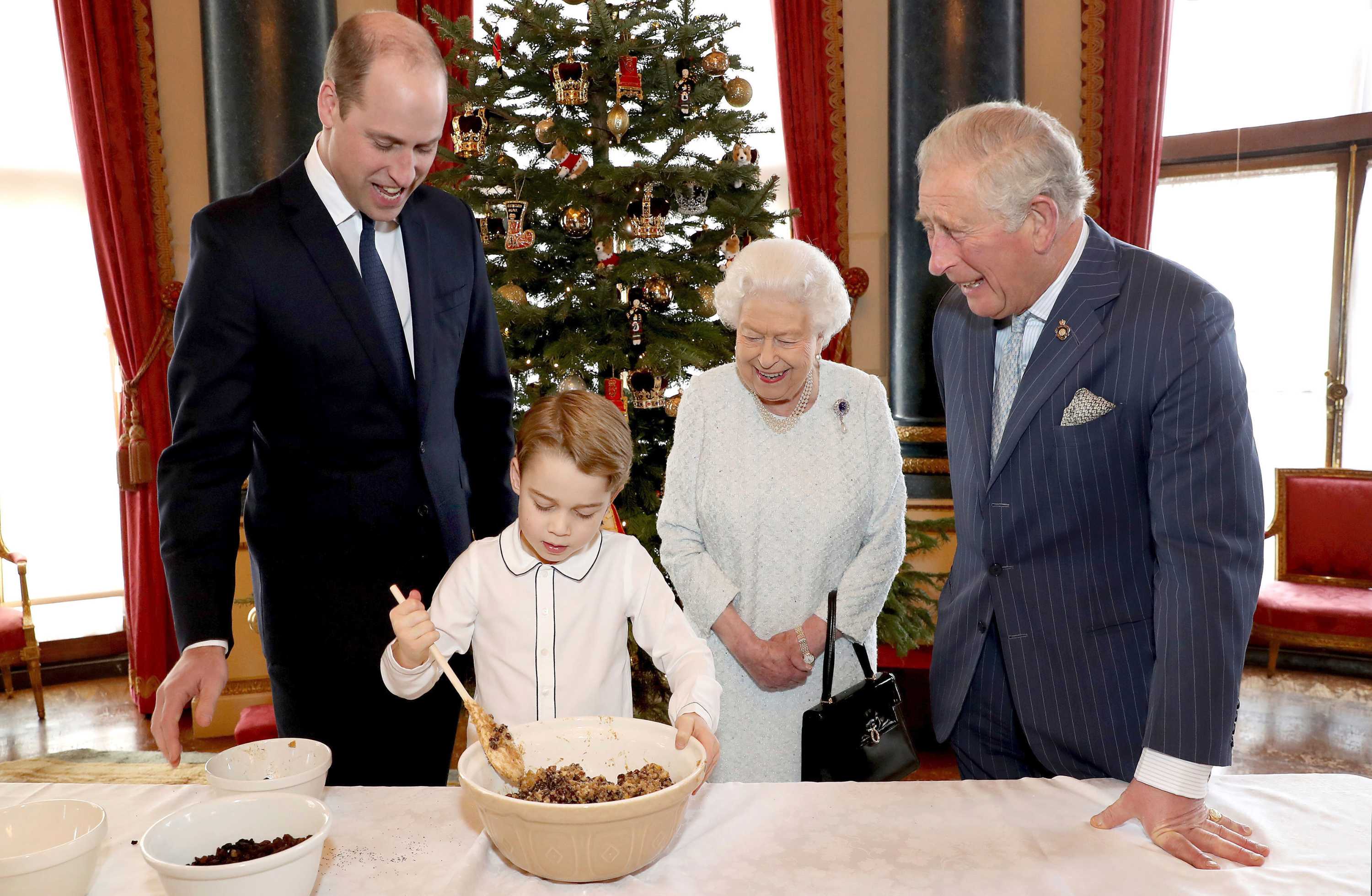 Queen Elizabeth, Prince Charles, Prince William stand around and Prince George as he stirs Christmas pudding mixture.