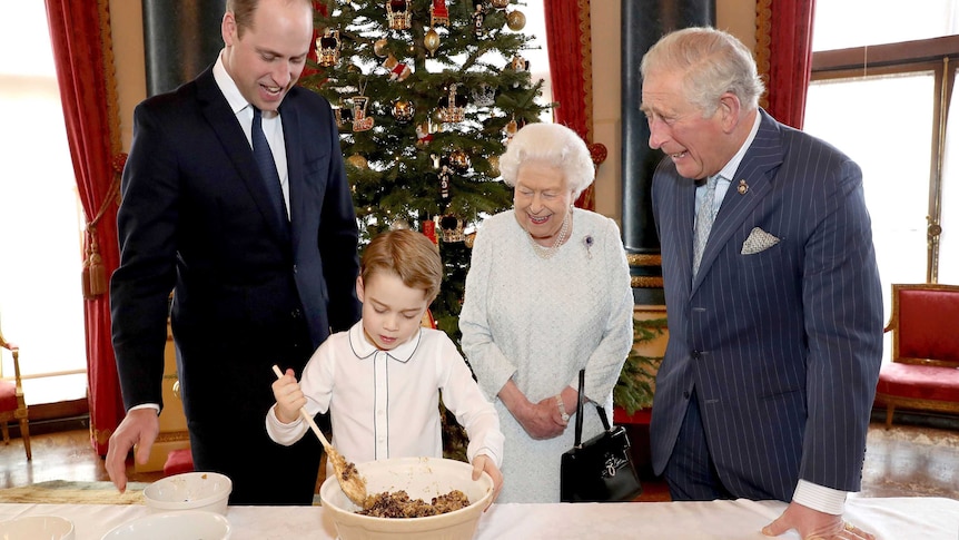 Queen Elizabeth, Prince Charles, Prince William stand around and Prince George as he stirs Christmas pudding mixture.