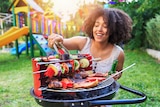 A woman cooking on a barbecue in the backyard.