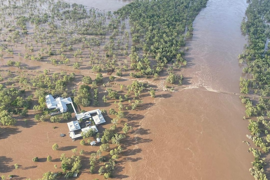 an aerial photo shows floodwaters surrounding accommodation and over a bridge