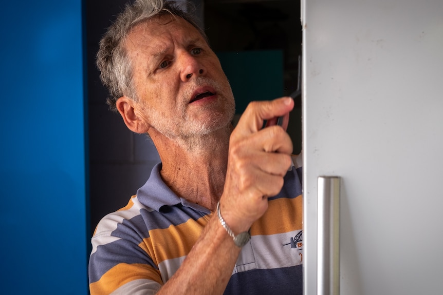 Man with toothbrush cleaning a fridge seal