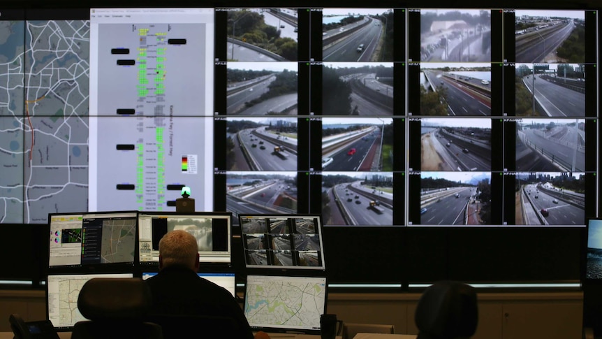 A man sits in front of screens at the Main Roads WA control room.